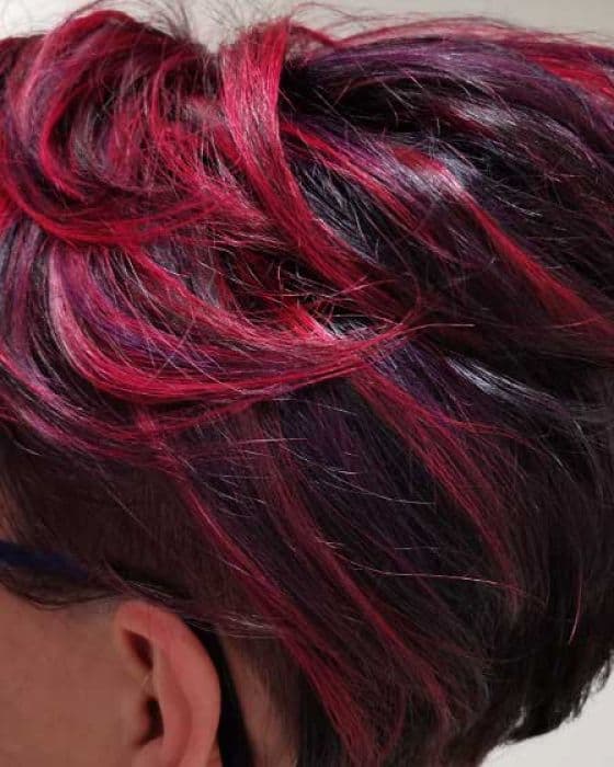 Kurzer dunkler Haarschnitt von oben mit leuchtend magentafarbenen Strähnen.